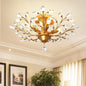 Gold coloured chandelier with crystal accents in a room with framed pictures and a plant.