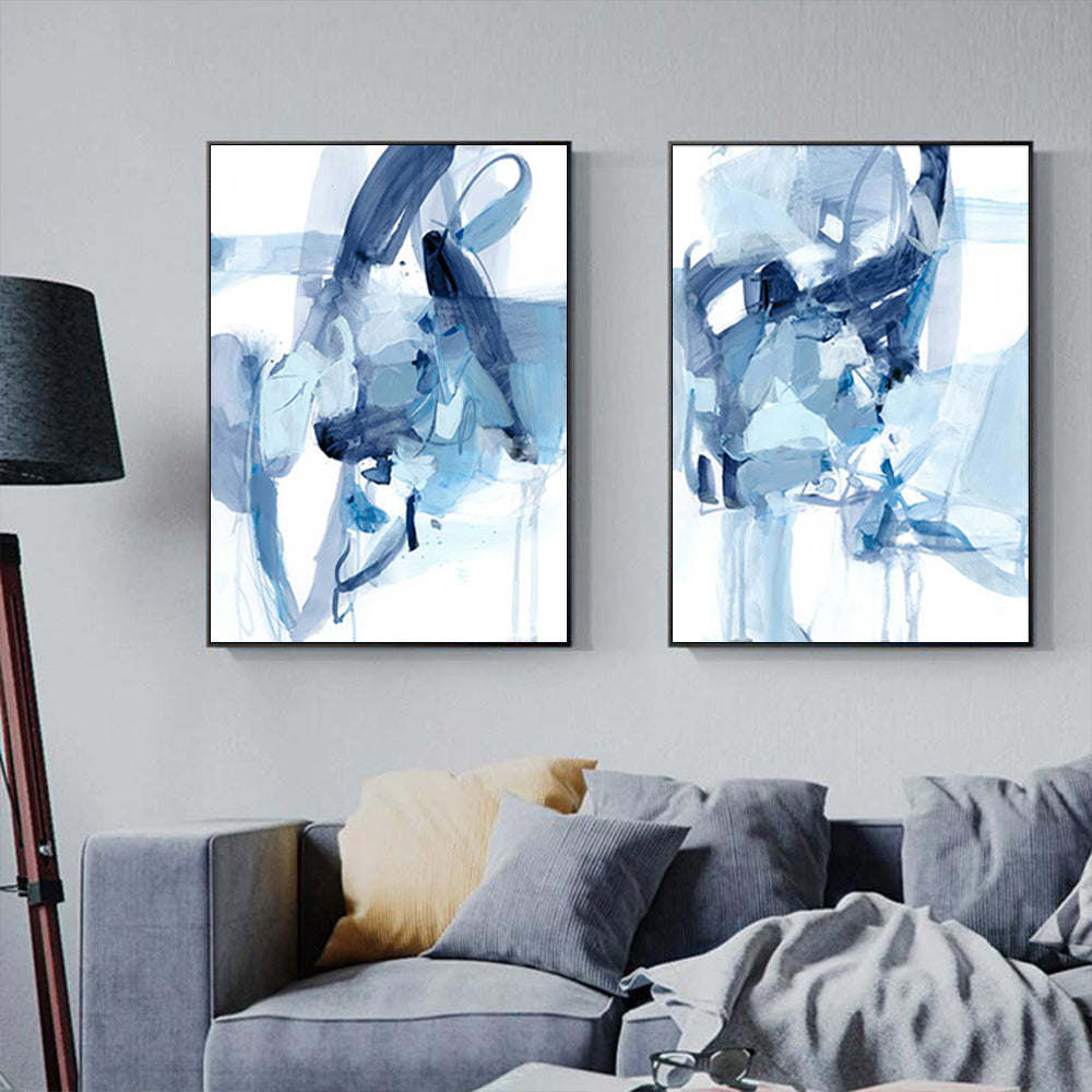 Two abstract blue artworks on a wall above a sofa.