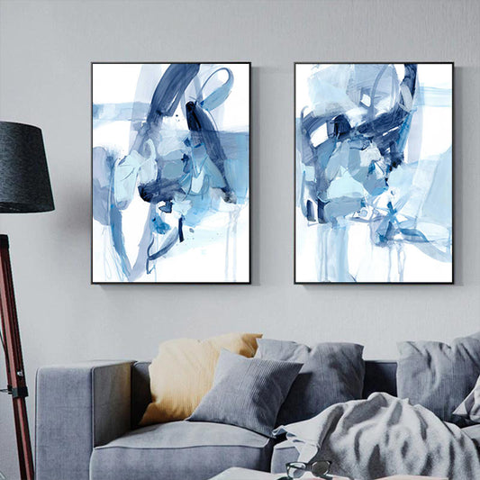 Two abstract blue artworks on a wall above a sofa.